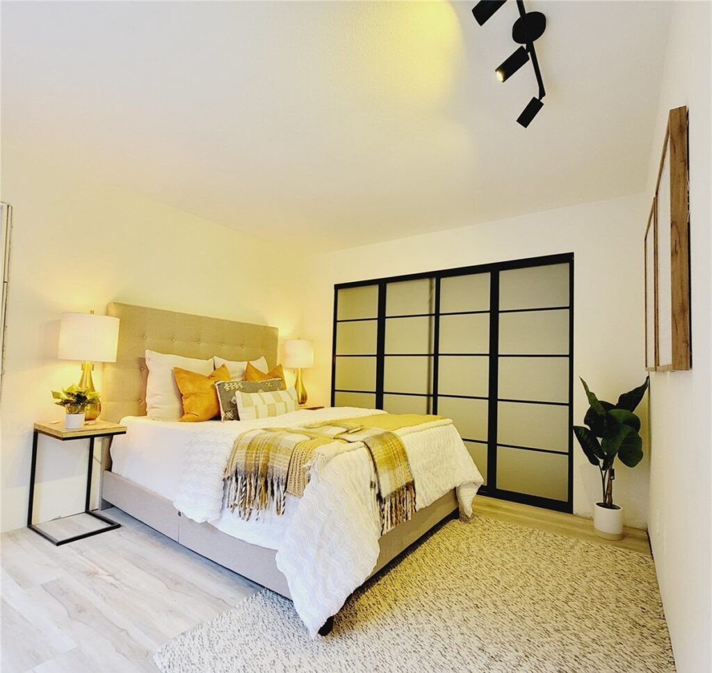 Bedroom with a tufted headboard, warm lamps and gold accent pillows