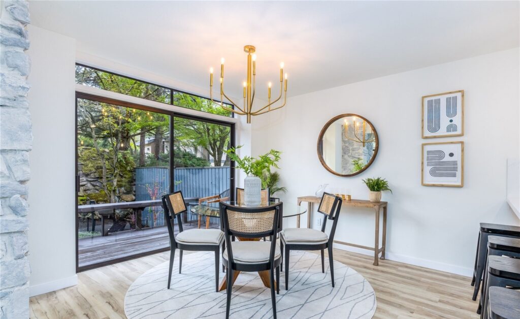 Dining nook with cane chairs, a round mirror and garden views