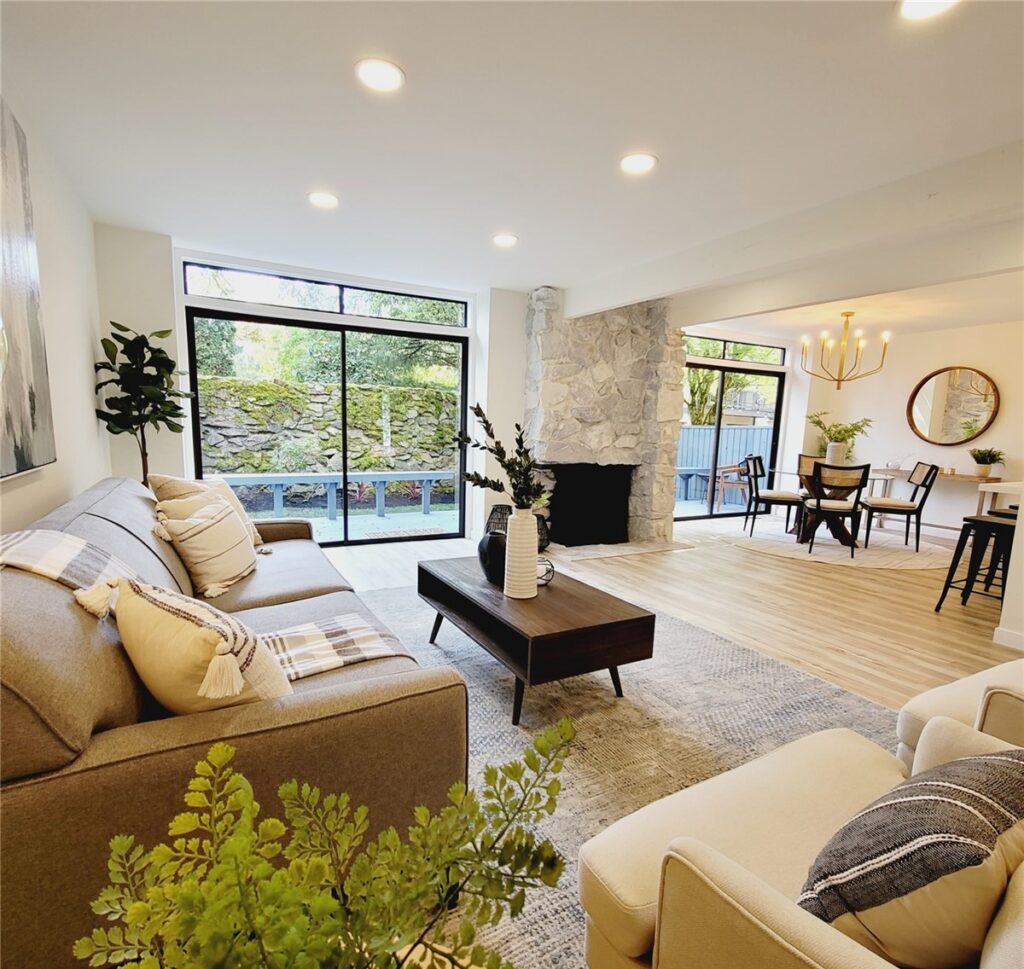 Living room arranged around a stone fireplace, with the dining table beyond