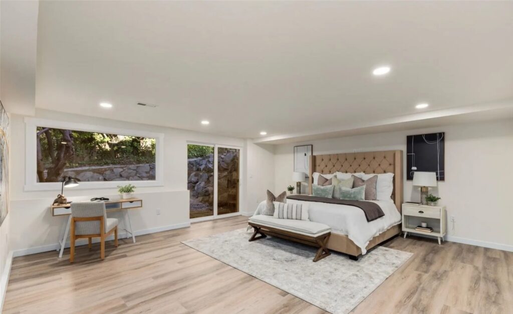 Bonus room staged as a downstairs primary bedroom with desk and sitting area in a Normandy Park home, by IntExt Staging