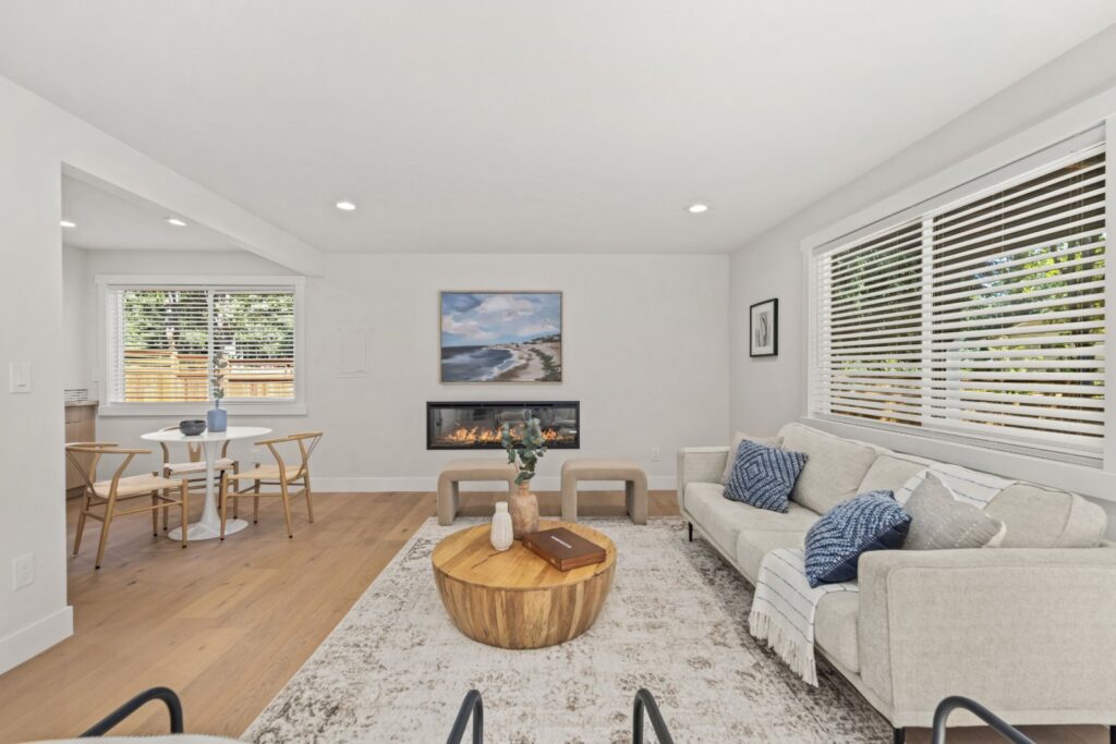 Lower-level living room staged with a sofa, lounge chairs and a round coffee table
