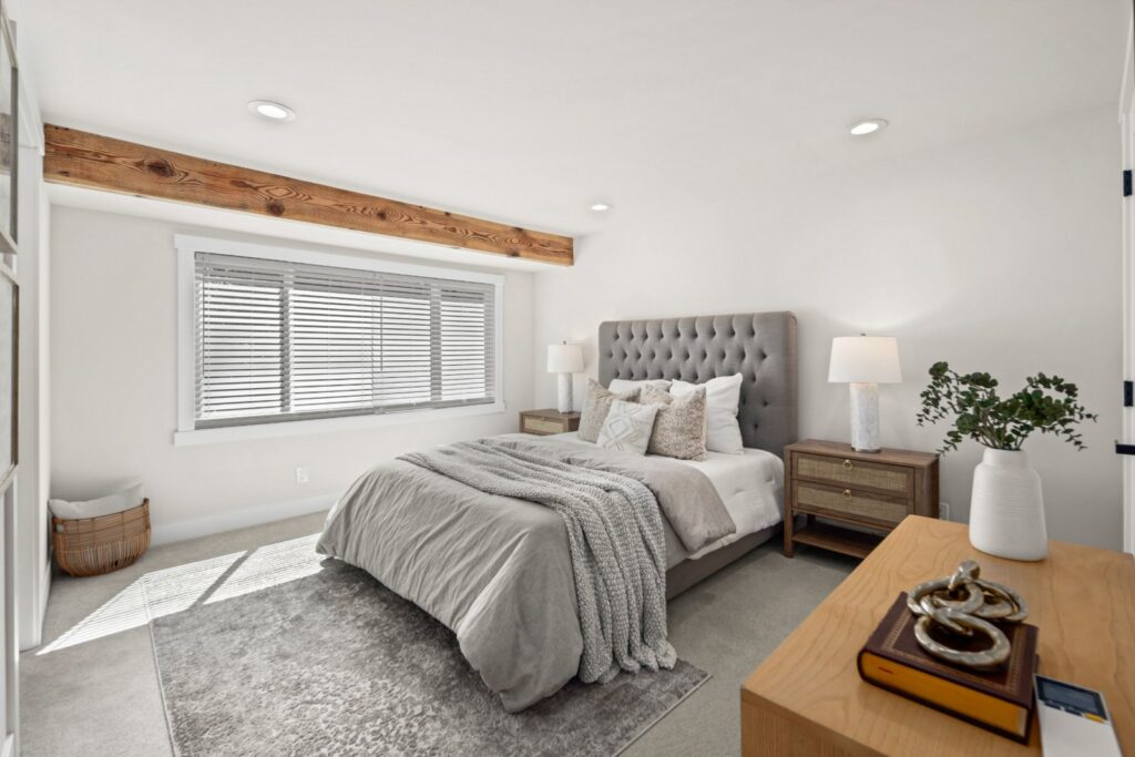 Primary bedroom with a tufted headboard, layered bedding and a wood beam