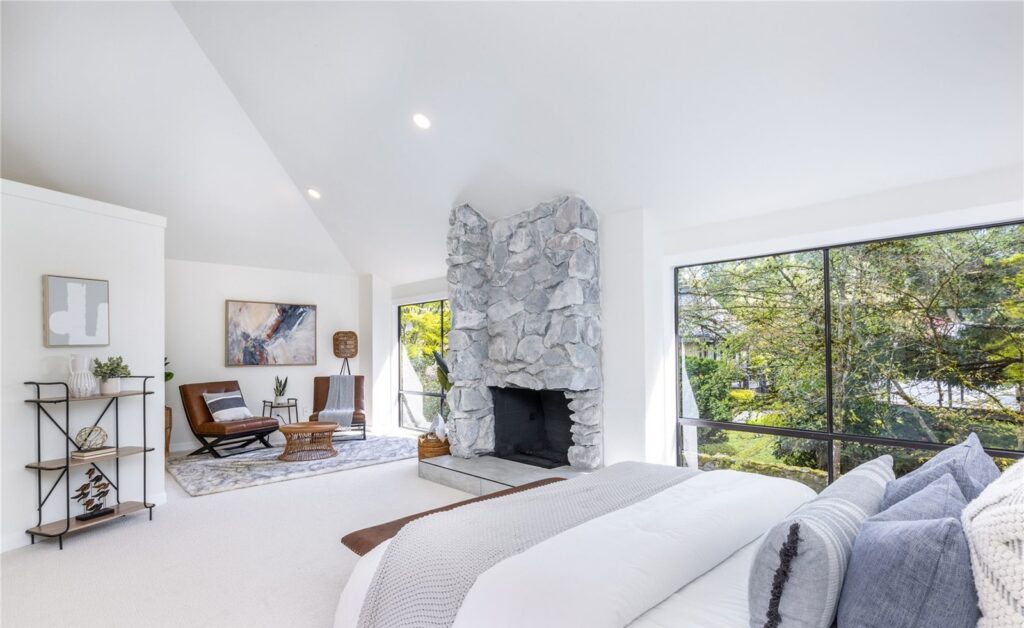Primary bedroom with real bed, layered bedding and stone fireplace in a Redmond home, staged by IntExt, a Seattle staging company
