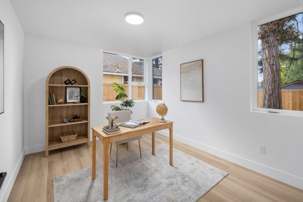 Den set up as an office with a desk, bookcase and rug, an example of vacant home staging
