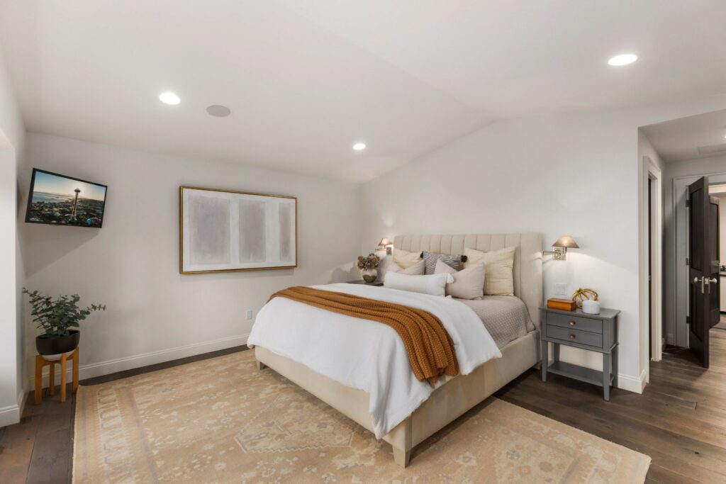 Staged bedroom with an upholstered headboard and layered bedding in a Seattle home, part of the home staging process by IntExt Staging